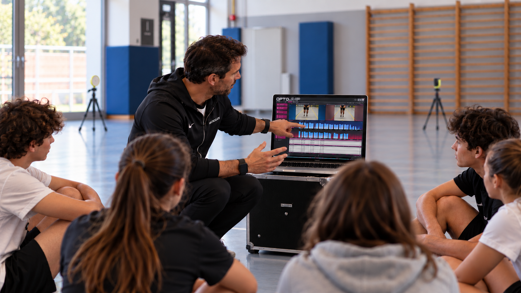 Un docente illustra agli studenti i dati di analisi del movimento sul computer, nella palestra scolastica